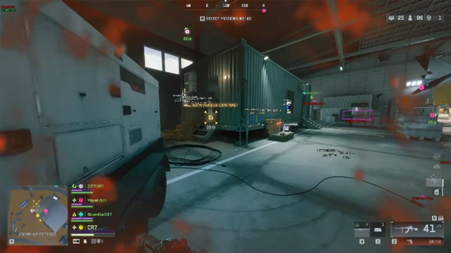 Battlefield 6 industrial hangar with a green command container, squad HUD, and damage vignette on screen.